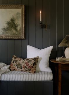 a couch with pillows and a lamp on the wall