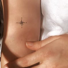 a woman's arm with a small compass tattoo on the left side of her body