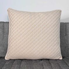 a beige pillow sitting on top of a gray couch