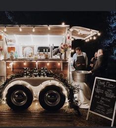 a food truck is decorated with lights and garlands for an outdoor wedding reception at night