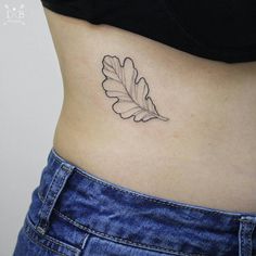 a woman's stomach with a leaf tattoo on it