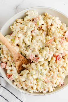 a white bowl filled with macaroni salad and a wooden spoon