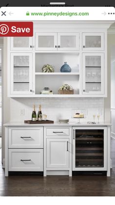 a kitchen with white cabinets and wine glasses on the counter top, along with two bottles of wine