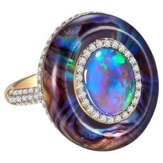 A 2.27 ct Solid Opal, Abalone Shell, Crystal and Diamond in 18k Yellow Gold. The solid opal is surrounded by a circle of diamond pave, on the outer circle is where the abalone shell is. The abalone shell is cover by thick crystal giving the ring a dome-like design. US Ring Size 8 Main opal weight is 2.27 ct Total diamond weight is 0.678 ct The diamonds are approximately E/F in colour with VS clarity Luxury Multicolor Cabochon Opal Ring, Luxury Opal Fusion Jewelry, Luxury Ethiopian Opal Fine Jewelry, Luxury Yellow Gold Opal Ring, Luxury Yellow Gold Opal Ring With Polished Finish, Luxury Oval Opal Ring For Anniversary, Luxury Polished Opal Ring, Oval Cabochon, Luxury Polished Opal Ring With Oval Cabochon, Luxury Opal Ring With Cabochon Cut