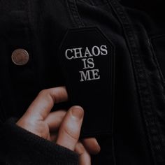 a person wearing a black jacket with the words chaos is me on it