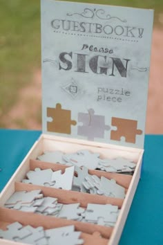 a wooden box filled with puzzle pieces sitting on top of a blue table covered in paper