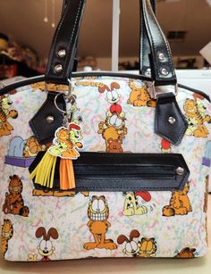 "Please note, pictured wallet is not included in this listing. This listing is for purse only, wallet is available in a separate listing. Introducing a delightful Garfield & Odie themed handbag, meticulously crafted to order. This unique purse combines a custom-made fabric featuring Garfield characters with vibrant vinyl accents. Created using the Lola pattern from Swoon patterns, this handbag is a testament to the utmost attention given to every detail, ensuring a high-quality accessory that yo Themed Multicolor Character Print Bags, Garfield Characters, Silly Garfield, Playful Multicolor Character Print Bags, Playful Multicolor Cartoon Print Bag, Disney Handbags Totes, Garfield Odie, Playful Multicolor Bags With Cat Design, Paw Wallpaper