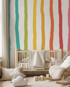 a baby's room with a crib, rocking chair and rainbow striped wallpaper