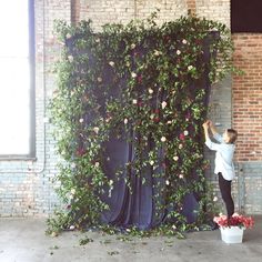 a young boy standing next to a giant flower covered wall in front of a window