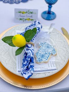 a plate with some lemons on it next to a blue glass and yellow napkin