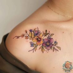 a woman's chest with flowers and leaves tattooed on the top of her breast