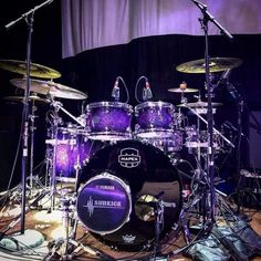 a purple drum set on stage with microphones