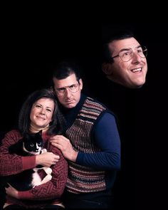 two people and a cat are posing for a photo in front of a black background