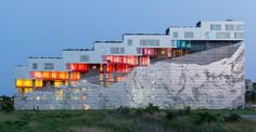 the building has many windows on it and is lit up with colorful lights at night