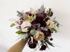 a bouquet of flowers is held up by someone's hand on a white background