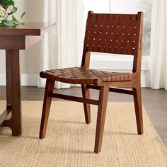 a wooden chair sitting on top of a rug in front of a table with a potted plant