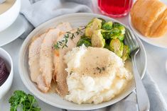 a white plate topped with meat and mashed potatoes next to other foods on a table