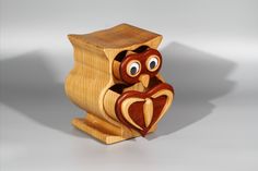 an owl made out of wood sitting on top of a wooden stand with its eyes open