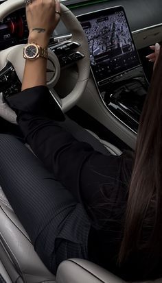 a woman sitting in the driver's seat of a car with her hands on the steering wheel