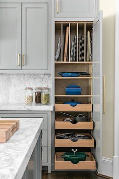 an organized kitchen with gray cabinets and white marble countertops