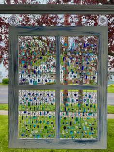 an old window is decorated with blue and green glass beads on the windowsills