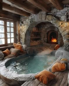 an indoor hot tub in the middle of a wood floored room with stone fireplace