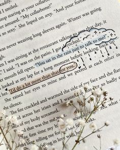 an open book with writing on it next to flowers