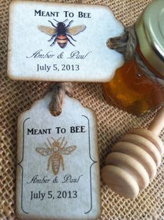 two honey jars with labels on them sitting next to a wooden spoon