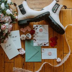 the wedding stationery is laid out on the floor with shoes and flowers next to it