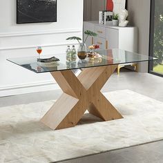 a glass and wood table in a living room with white rugs on the floor