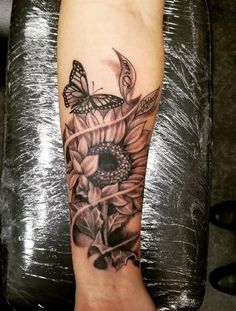 a woman's foot with a butterfly and sunflower tattoo on it