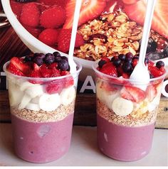 two cups filled with yogurt and fruit on top of a table next to a poster