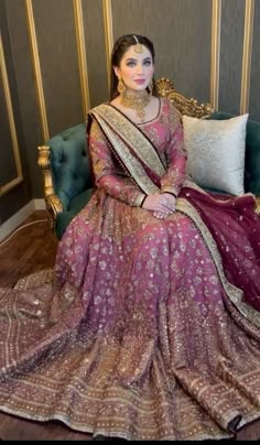 a woman sitting on top of a couch wearing a purple and gold dress with an elaborate headpiece