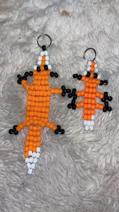 two orange and white beaded keychains sitting on top of a furry surface