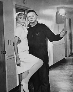 an old black and white photo of two people posing for the camera in a hallway