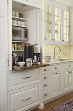 a kitchen with white cabinets and wood flooring is pictured in this image, there is a coffee maker on the counter