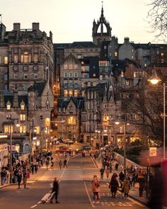 many people are walking down the street at dusk