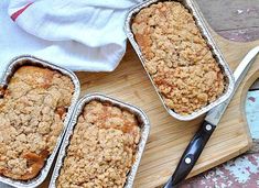 three pans filled with food sitting on top of a wooden cutting board