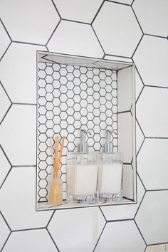 the bathroom is decorated with white hexagonal tiles and gold accessories, including two soap dispensers