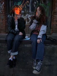 two people sitting on a bench with their faces lit up by string lights in front of them