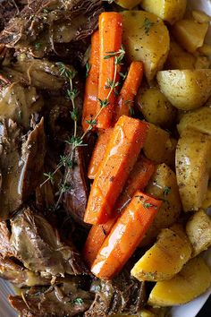 a white plate topped with roast, potatoes and carrots