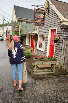 the woman is walking down the street carrying her shopping bag and looking at the store