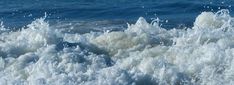 the water is splashing on top of the rocks in the ocean, and it looks like they are crashing