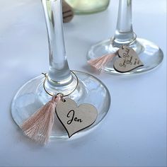 two wine glasses with tassels and tags on them sitting next to each other