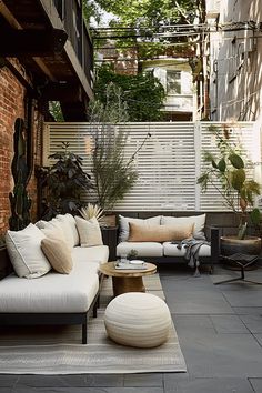 an outdoor living area with couches, tables and plants on the side of the building