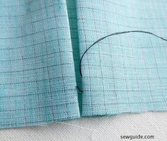 the sewing needle is being used to sew on some blue fabric, which has been stitched together