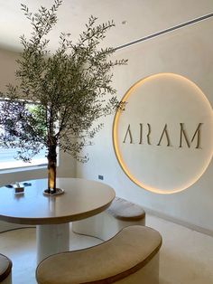 a round table with two benches and a vase on it in front of a sign that reads aram