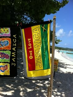 two beach towels hanging from a tree on the beach