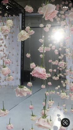 pink and white flowers are suspended from the ceiling in front of a mirror with light shining on them