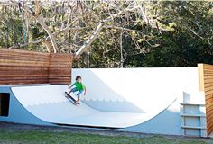 a man riding a snowboard down the side of a ramp on top of grass